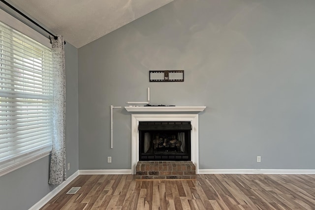 unfurnished living room featuring dark hardwood / wood-style flooring, a brick fireplace, and lofted ceiling