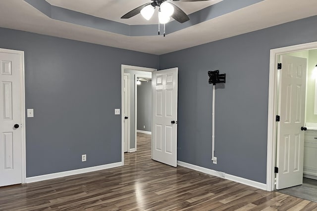 unfurnished bedroom featuring ceiling fan, a tray ceiling, and dark hardwood / wood-style flooring