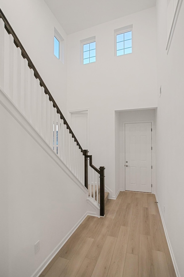 entryway featuring a towering ceiling and light wood-type flooring