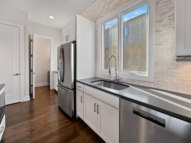 kitchen featuring sink, dark wood-type flooring, appliances with stainless steel finishes, white cabinetry, and decorative backsplash