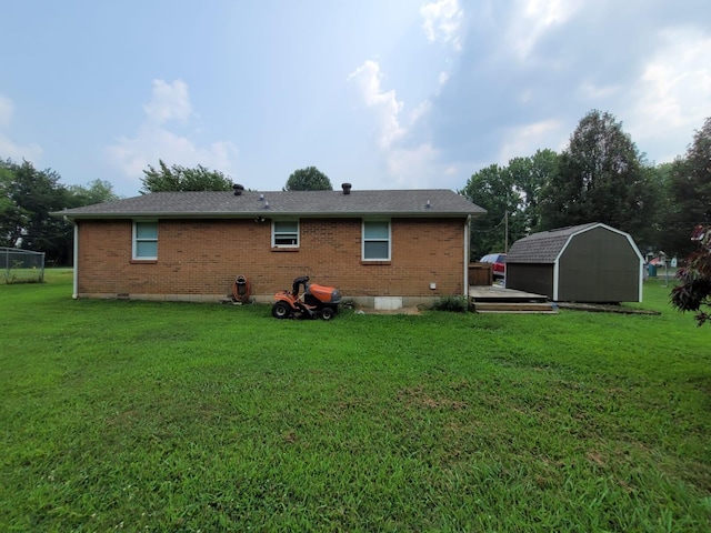 rear view of property featuring a yard, an outdoor structure, a deck, a storage shed, and brick siding