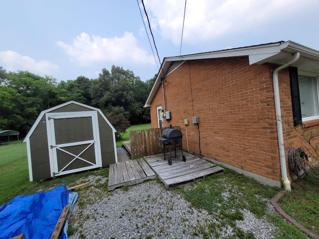 view of side of property featuring an outdoor structure, a storage unit, brick siding, and a wooden deck