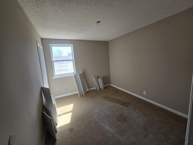 spare room featuring baseboards, carpet floors, and a textured ceiling