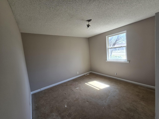 carpeted spare room featuring visible vents, baseboards, and a textured ceiling