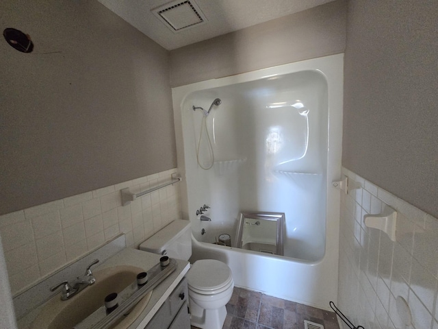 full bathroom with vanity, washtub / shower combination, visible vents, tile walls, and toilet