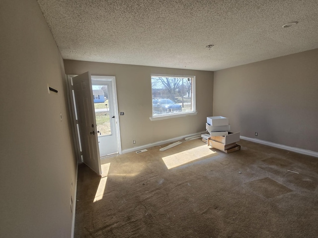 carpeted empty room with visible vents, baseboards, and a textured ceiling