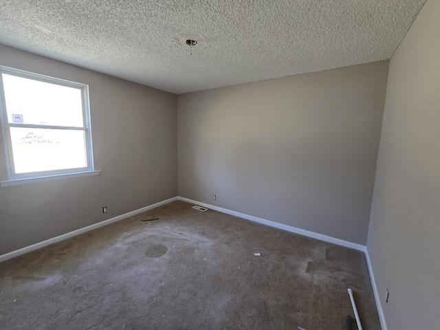 carpeted spare room featuring visible vents, a textured ceiling, and baseboards