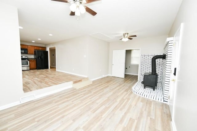 118 Rainbow St, Clarksville, TN 37042 - unfurnished living room featuring light wood finished floors, visible vents, a ceiling fan, a wood stove, and baseboards