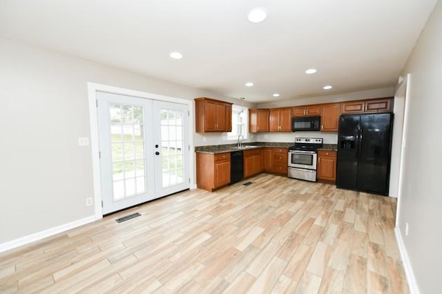 kitchen with dark countertops, black appliances, light wood finished floors, and french doors