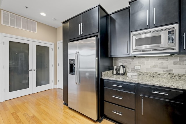 kitchen featuring french doors, tasteful backsplash, stainless steel appliances, and light stone counters