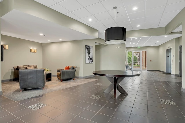 playroom with dark tile patterned floors, elevator, and a drop ceiling