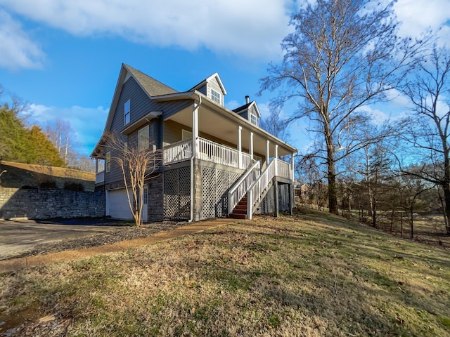 back of property with a porch, a garage, and a yard