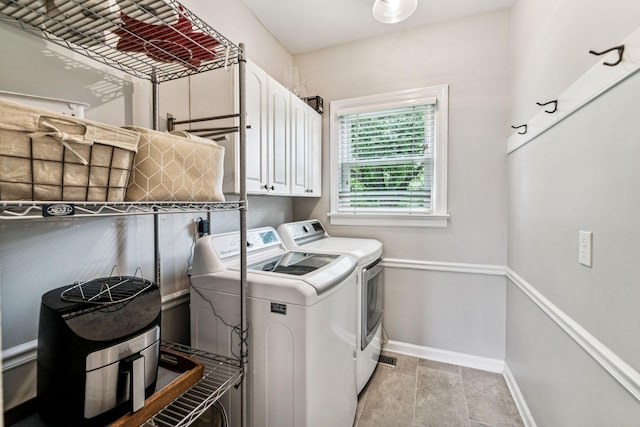 clothes washing area with washing machine and dryer and cabinets