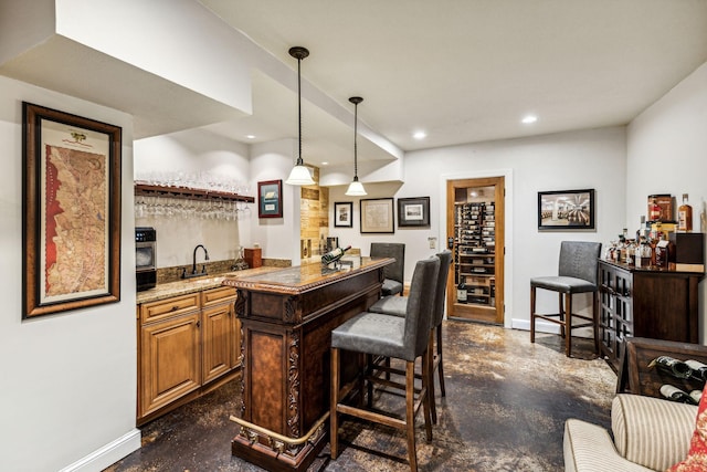 bar featuring decorative light fixtures, oven, sink, and light stone countertops