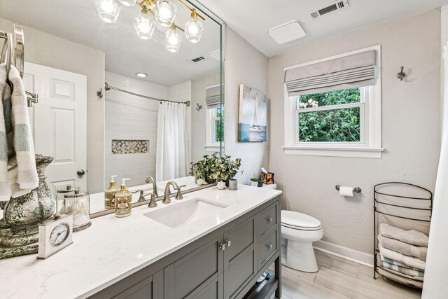 bathroom with hardwood / wood-style flooring, vanity, walk in shower, toilet, and an inviting chandelier