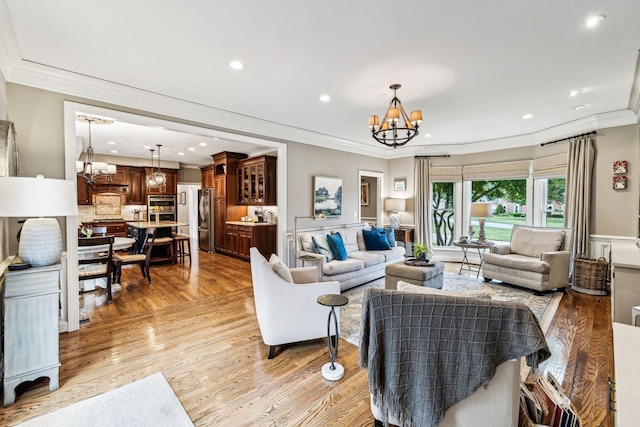 living room featuring ornamental molding, a chandelier, and light wood-type flooring