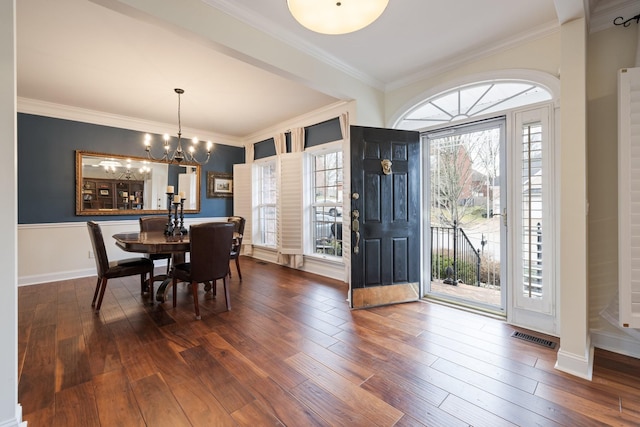 foyer featuring crown molding, hardwood / wood-style floors, and a notable chandelier