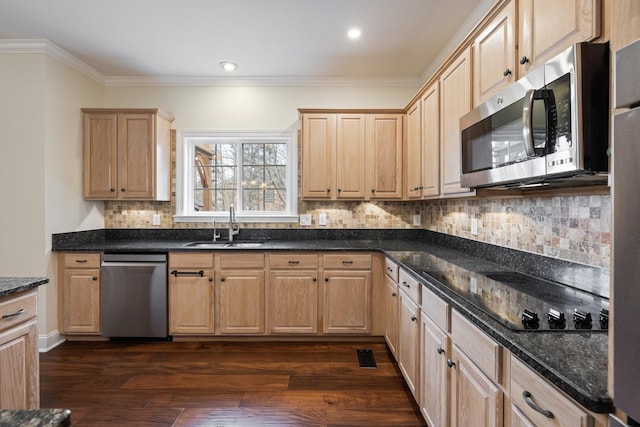 kitchen with appliances with stainless steel finishes, sink, dark wood-type flooring, and dark stone counters