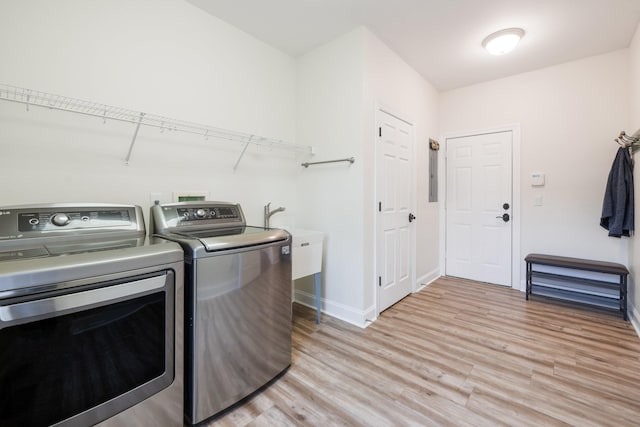 laundry area featuring independent washer and dryer, sink, and light hardwood / wood-style floors