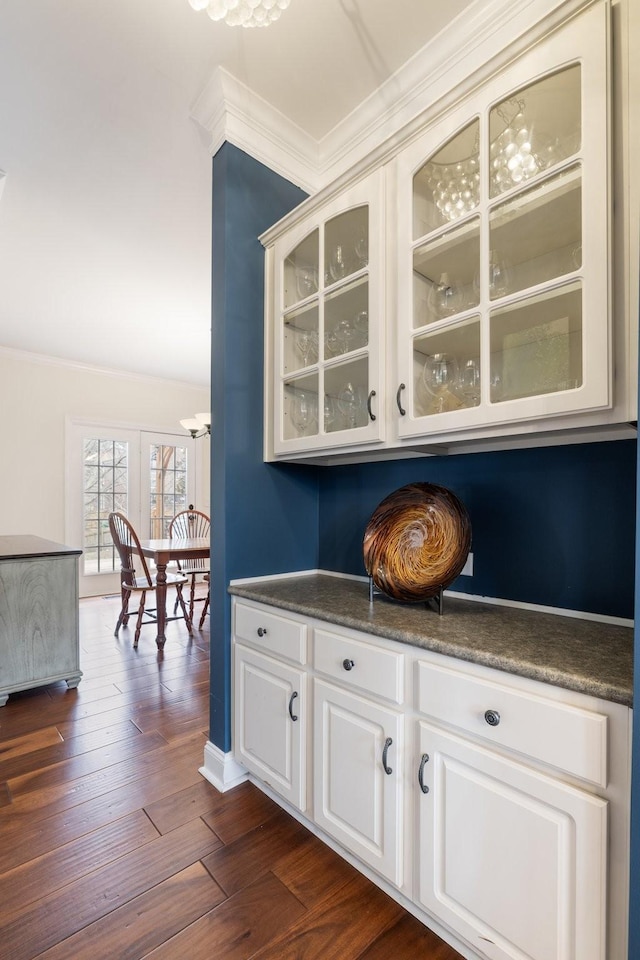 bar featuring dark wood-type flooring, crown molding, and white cabinets