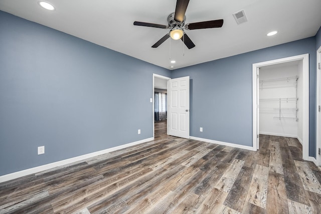 unfurnished bedroom featuring dark hardwood / wood-style flooring, a spacious closet, a closet, and ceiling fan