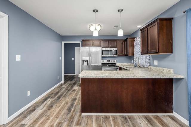 kitchen featuring sink, hanging light fixtures, dark brown cabinets, appliances with stainless steel finishes, and kitchen peninsula