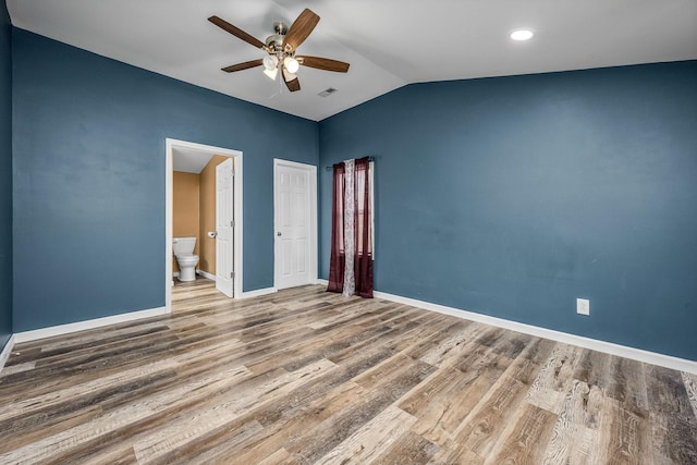 unfurnished bedroom featuring connected bathroom, hardwood / wood-style floors, vaulted ceiling, and ceiling fan