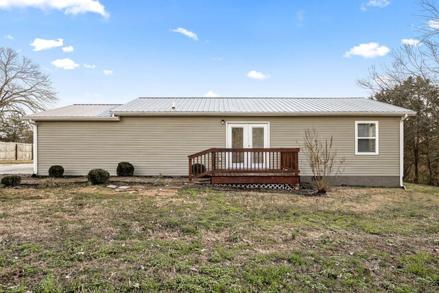 rear view of house with a wooden deck, a lawn, and french doors