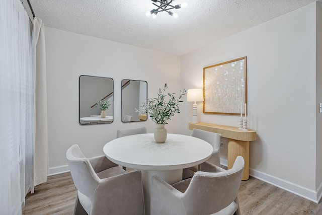 dining area featuring light hardwood / wood-style flooring and a textured ceiling