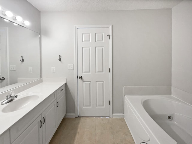 bathroom with tile patterned flooring, vanity, a textured ceiling, and a tub to relax in