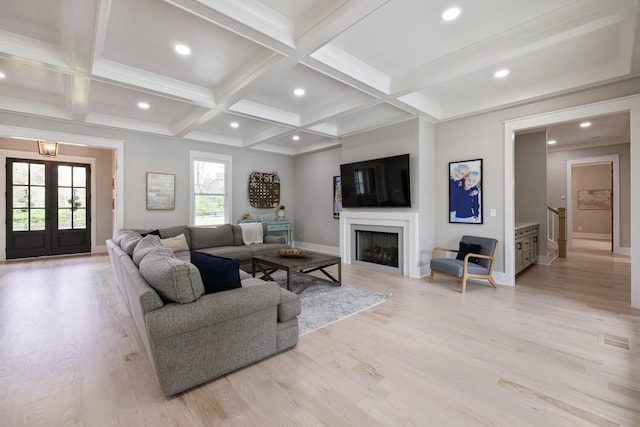 living room with light wood-type flooring, coffered ceiling, beam ceiling, and french doors