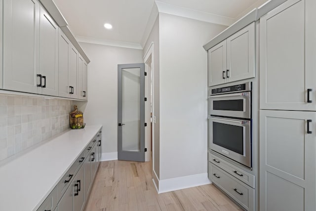 kitchen featuring gray cabinetry, tasteful backsplash, light hardwood / wood-style flooring, ornamental molding, and double oven