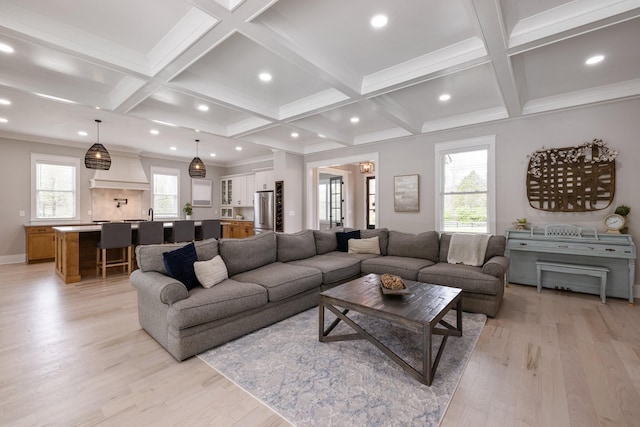 living room with coffered ceiling, ornamental molding, light hardwood / wood-style floors, and beamed ceiling