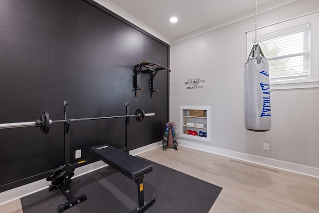 workout area featuring built in shelves, ornamental molding, and light hardwood / wood-style floors