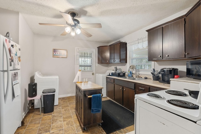 kitchen featuring sink, white appliances, dark brown cabinets, washing machine and dryer, and a center island