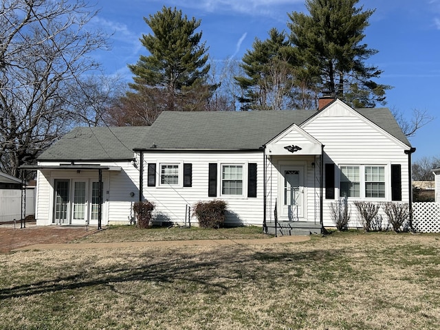 view of front facade with roof with shingles, a chimney, french doors, and a front yard