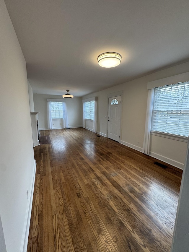 interior space featuring dark wood-style floors, baseboards, a fireplace, and visible vents