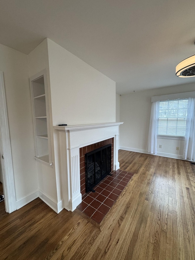 unfurnished living room with a fireplace, wood finished floors, and baseboards