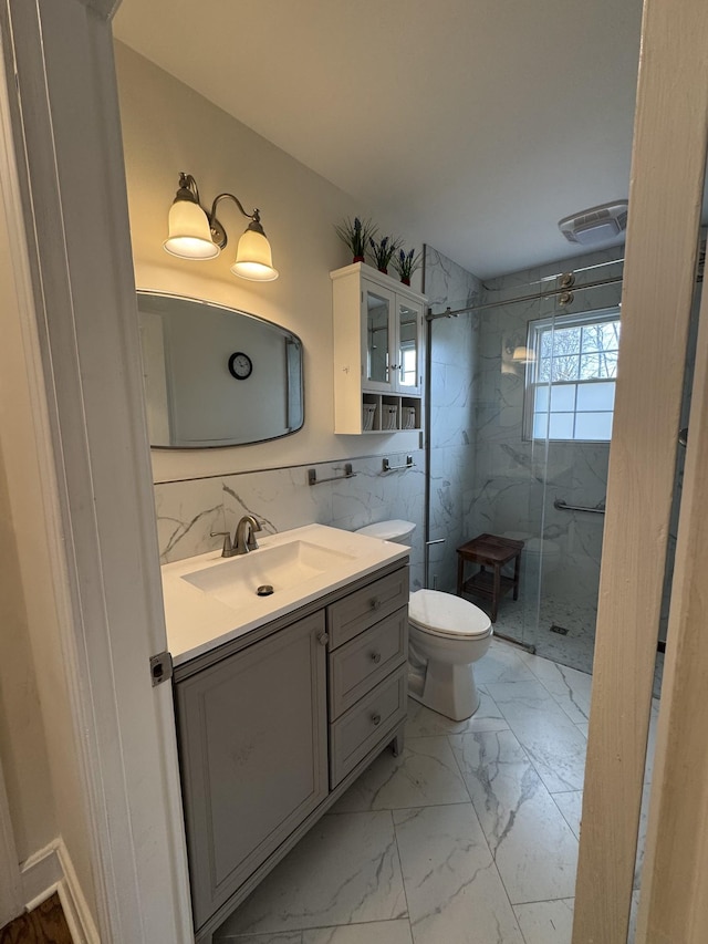 full bath featuring toilet, vanity, tile walls, marble finish floor, and a marble finish shower