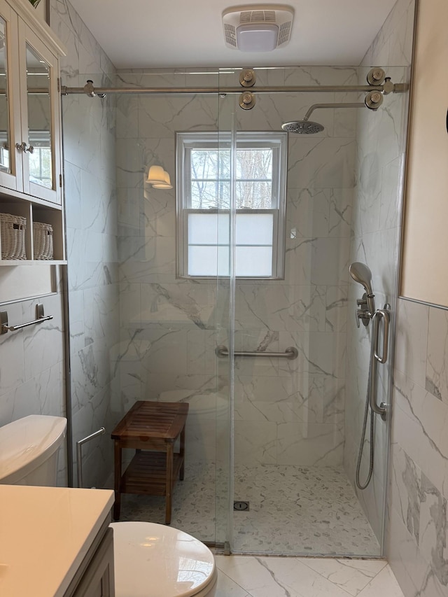 bathroom featuring a marble finish shower, vanity, and toilet