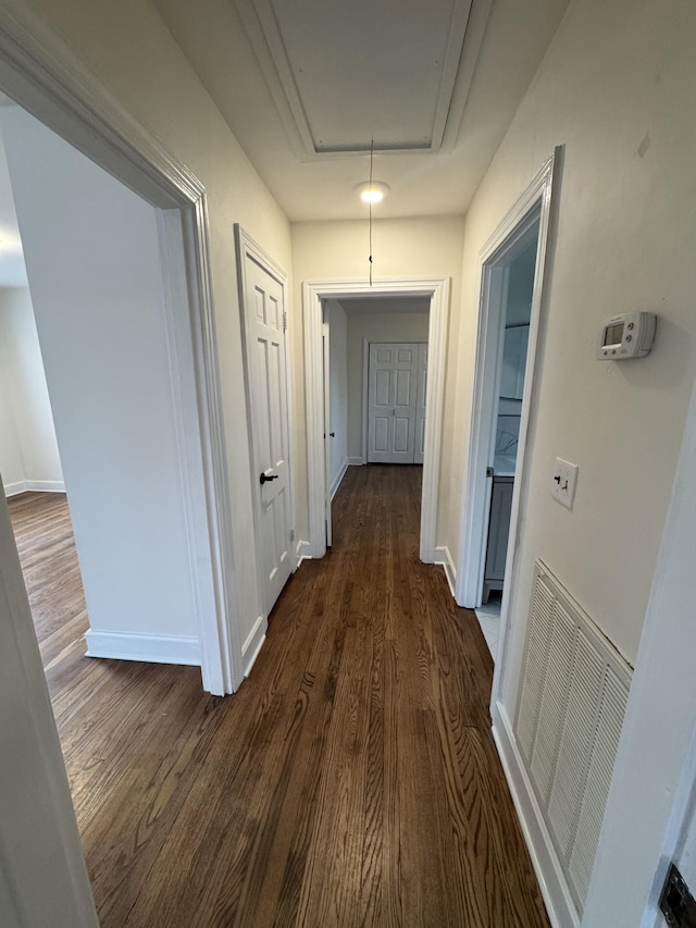 corridor featuring attic access, visible vents, dark wood finished floors, and baseboards