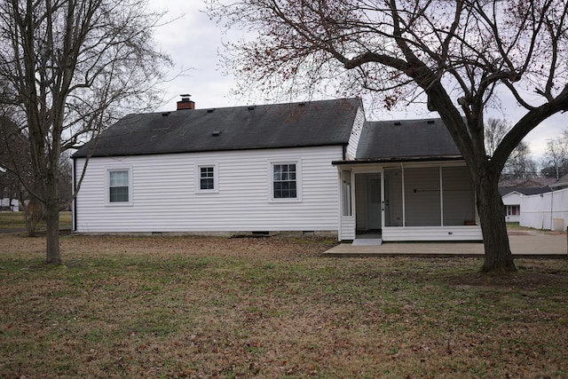 rear view of property featuring crawl space, a sunroom, a chimney, and a yard