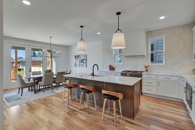 kitchen with white cabinetry, pendant lighting, sink, and a center island with sink