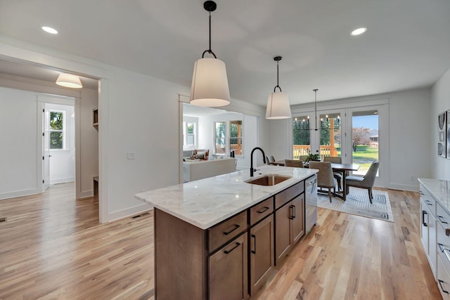 kitchen with sink, light hardwood / wood-style flooring, dishwasher, hanging light fixtures, and light stone countertops