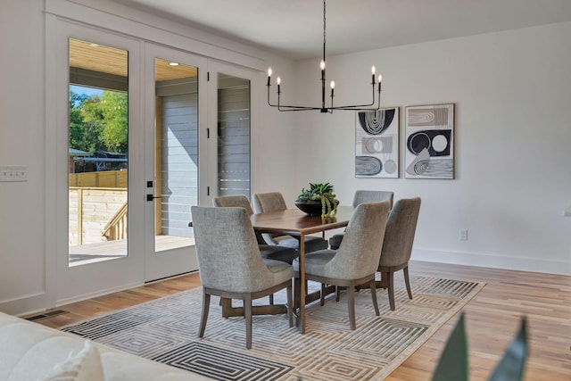 dining room with french doors, an inviting chandelier, and light hardwood / wood-style flooring