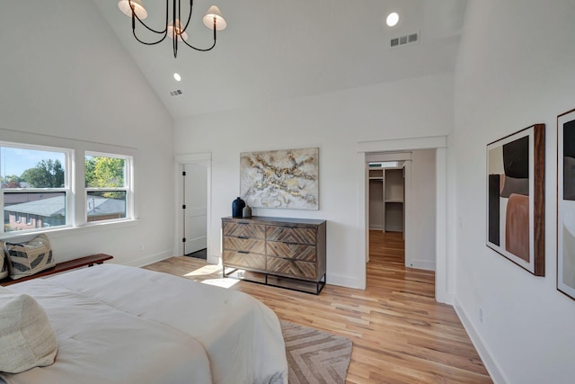 bedroom with high vaulted ceiling, a chandelier, and light wood-type flooring