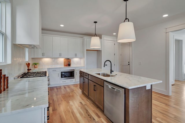 kitchen with sink, an island with sink, white cabinets, and appliances with stainless steel finishes