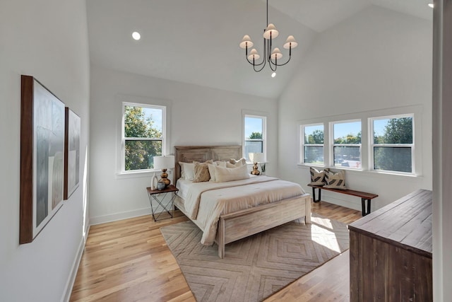 bedroom with a notable chandelier, high vaulted ceiling, and light wood-type flooring