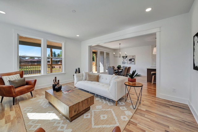 living room featuring plenty of natural light, a chandelier, and light hardwood / wood-style flooring