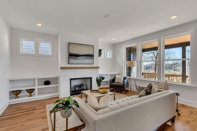 living area featuring baseboards, a fireplace, wood finished floors, and recessed lighting